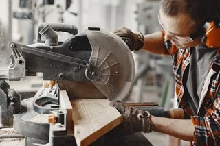 Carpenter working with circular saw Wood cutting with circular saw. Closeup of mature man sawing lumber.