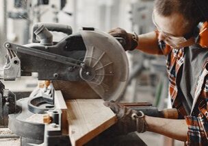 Carpenter working with circular saw Wood cutting with circular saw. Closeup of mature man sawing lumber.